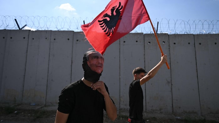 Demonstranten mit der kosovarischen Flagge und einer Thaci-Maske vor dem Hauptquartier der ...