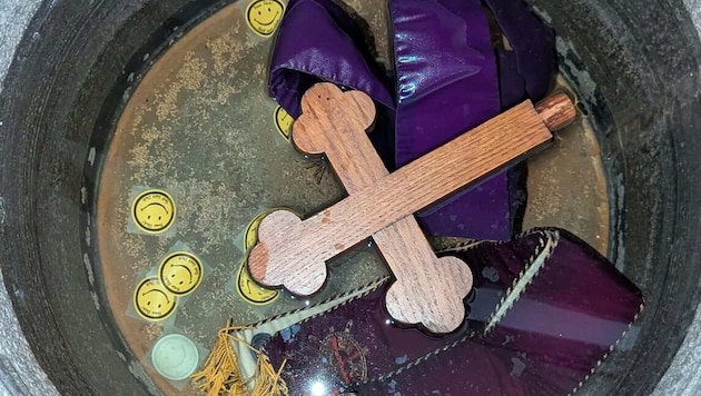 A cross and two priestly stoles were submerged in the holy water font.