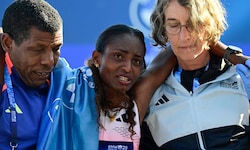 Tigst Assefa (M.) muss nach ihrem Sieg beim Berlin-Marathon von Helfern gestützt werden …