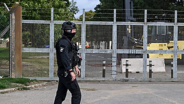 Ein schwer bewaffneter Polizist vor dem verriegelten Einfahrtstor der Basis RAF Fairford