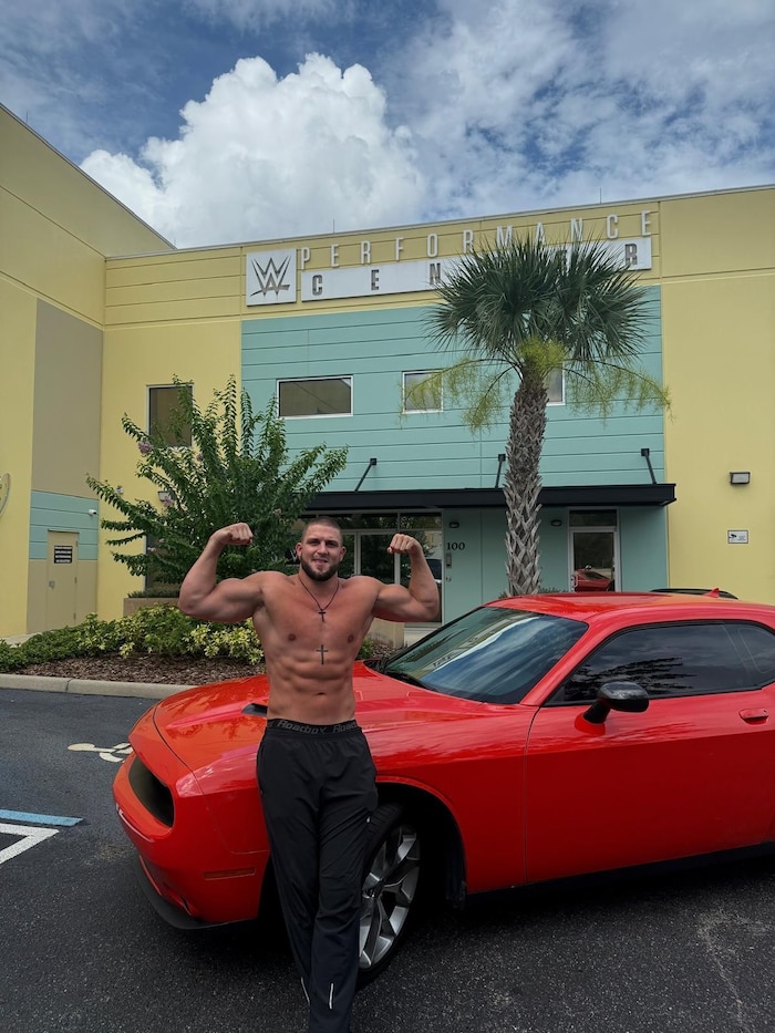 Aaron Fara mit seinem roten Dodge Challenger vor dem WWE-Performance Center in Orlando.
