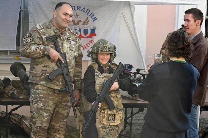 Kinder posieren in Uniform und mit Waffen.