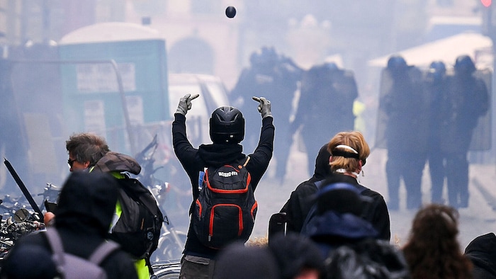 Eindeutige Geste in Richtung der Sicherheitskräfte, die mit Tränengasgranaten schießt.