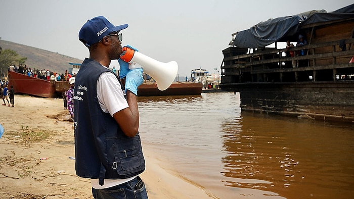 Ein Mitarbeiter des Gesundheitsdienstes gibt den Passagieren eines Wassertaxis im Fluss Kongo ...