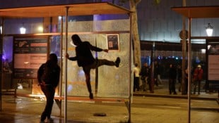 Demonstrierende schlagen eine Busstation in Barcelona kaputt.