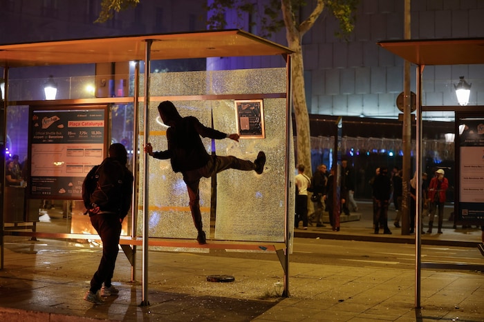 Demonstrierende schlagen eine Busstation in Barcelona kaputt.