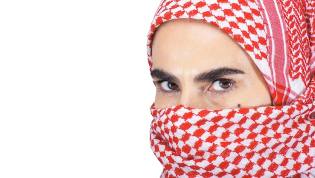 Mit solch einem roten Tuch, als „Kufiya“ bekannt, hat die Frau ihr Gesicht verhüllt ...