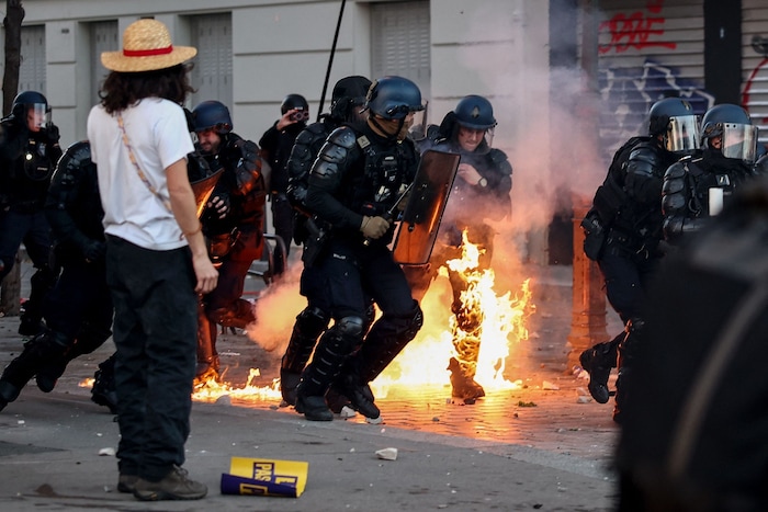 Die Beine eines Polizisten in Paris stehen während der Halloween-Demo in Flammen.