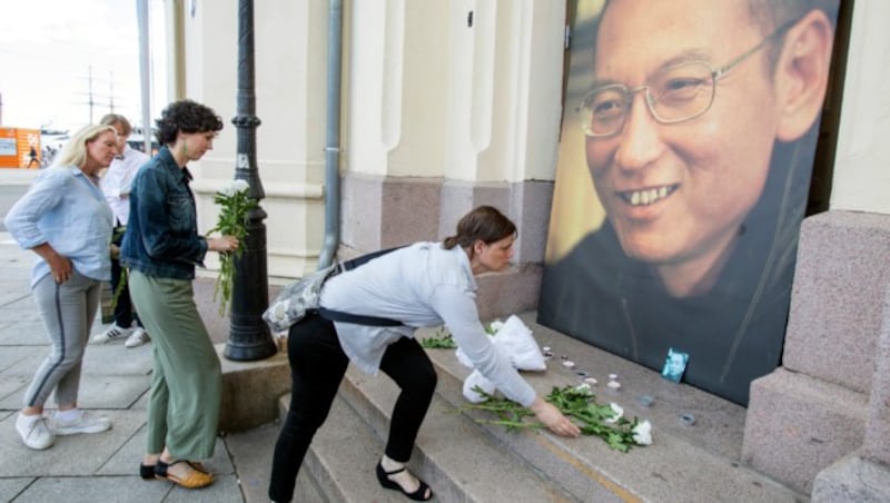 Passanten legen Blumen vor einem Porträt Lius beim Osloer Nobel Friedenszentrum nieder. (Bild: AP)