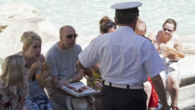 Touristen werden von einem Polizisten aufgefordert, nicht am Trevi-Brunnen Pizza zu essen. (Bild: EPA)
