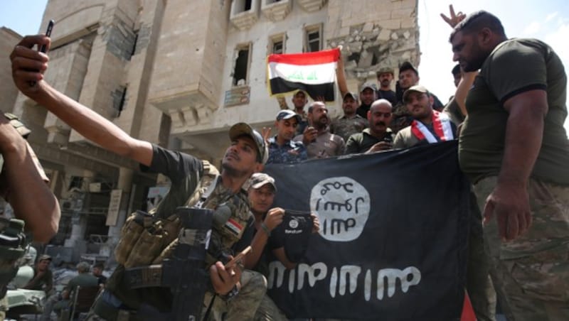 Irakische Soldaten posieren vor einer IS-Flagge. (Bild: AFP)