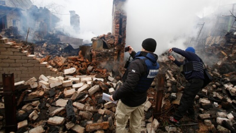 OSZE-Mitarbeiter machen Bilder von der zerstörten Stadt Awdijiwka (Bild: AFP)