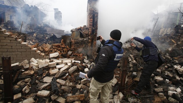 OSZE-Mitarbeiter machen Bilder von der zerstörten Stadt Awdijiwka (Bild: AFP)