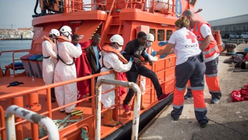 Flüchtlinge werden nach ihrer Rettung von Bord eines Schiffs der spanischen Küstenwache gebracht. (Archivbild) (Bild: AFP)