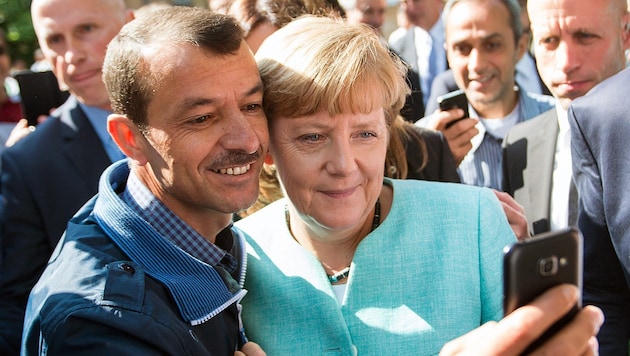 Angela Merkel mit einem Flüchtling im Jahr 2015 (Bild: APA/EPA/BERND VON JUTRCZENKA)