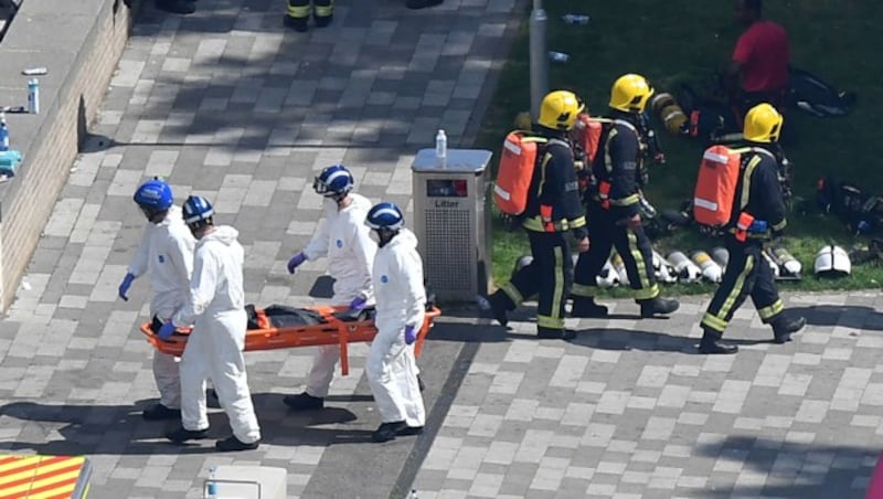 Helfer transportieren eine Leiche vom Gelände ab. (Bild: AFP)