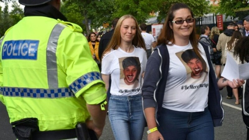 Zwei Mädels tragen bedruckte Shirts, die einen Freund zeigen, der bei dem Anschlag umgekommen ist. (Bild: AFP or licensors)