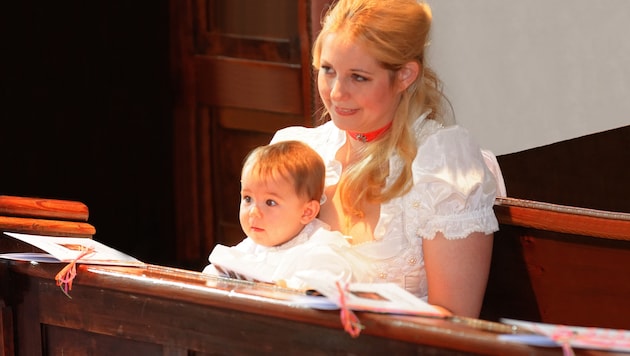 Mit großen Augen sitzt Victoria Katharina Luise Schell bei ihrer Taufe am Schoß ihrer Mama Iva. (Bild: Josef Bart)