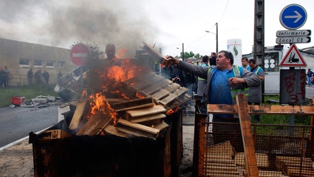 Arbeiter errichten Barrikaden aus brennenden Paletten. (Bild: AFP)