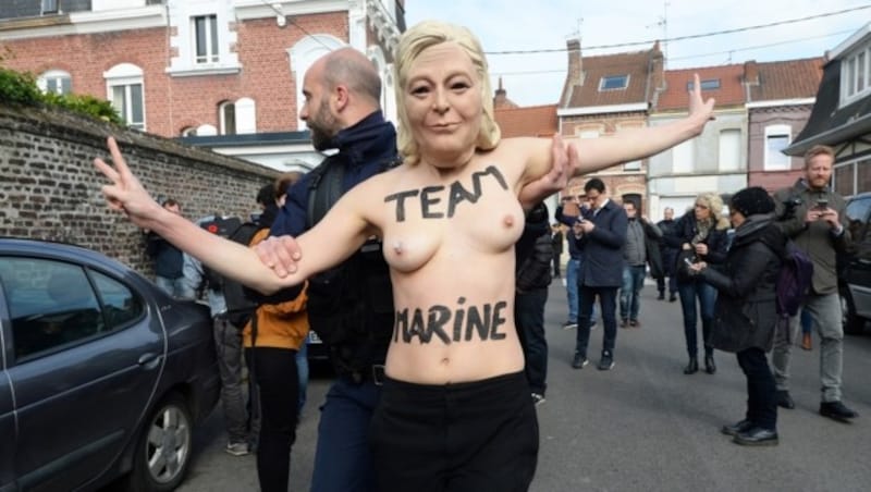 Eine entblößte Femen-Aktivistin mit einer Maske von Marine Le Pen (Bild: AFP)