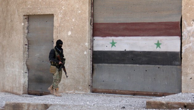 Ein syrischer Rebell vor einem Graffiti, das die Landesflagge zeigt (Bild: AFP)