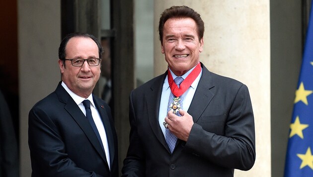 Schwarzenegger posiert stolz mit seiner Auszeichnung neben Frankreichs Präsident Hollande. (Bild: AFP)
