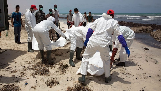 Helfer bergen Leichen an der libyschen Küste. (Bild: AFP)