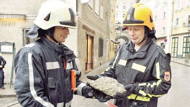 Feuerwehrmänner mit einem der Steine aus der Mönchsbergwand, die in der Gstättengasse landeten. (Bild: Info-Z/Killer)