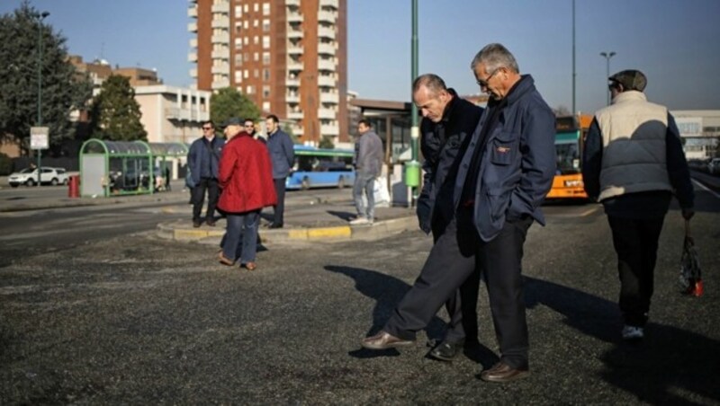 Passanten begutachten die Blutspuren auf dem Asphalt. (Bild: APA/AFP/MARCO BERTORELLO)