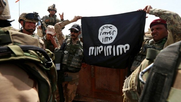 Irakische Soldaten mit einer auf den Kopf gestellten IS-Flagge (Bild: APA/AFP/SAFIN HAMED)