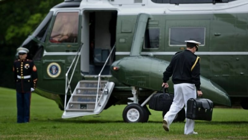 Ein Militäradjutant trägt den Atomkoffer in seiner rechten Hand zum Hubschrauber des US-Präsidenten. (Bild: APA/AFP/BRENDAN SMIALOWSKI)