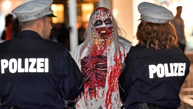Ein Teilnehmer des Zombie-Walk in Essen mit zwei Polizisten (Bild: Associated Press)