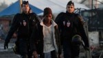 Ein junger Flüchtling wird von zwei französischen Polizisten aus dem Lager von Calais begleitet. (Bild: ASSOCIATED PRESS)