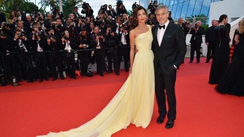 George Clooney hält seine Frau Amal im Arm, die ein Kleid von Atelier Versace gewählt hat. (Bild: AFP)
