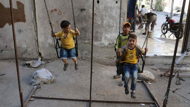 Spielende Kinder in einer von Rebellen gehaltenen Vorstadt von Damaskus (Bild: APA/AFP/AMER ALMOHIBANY)