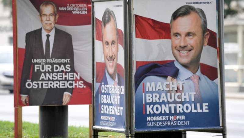 Van der Bellen und Hofer lächeln von Wahlplakaten. (Bild: APA/ROLAND SCHLAGER)