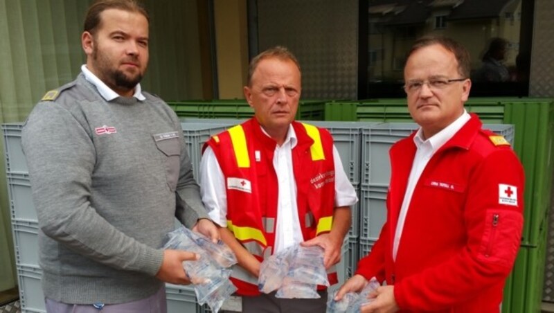Georg Tazoll, Martin Taupe und Fabian Finding vom Roten Kreuz mit Wasserpaketen. (Bild: Fritz Kimeswenger)
