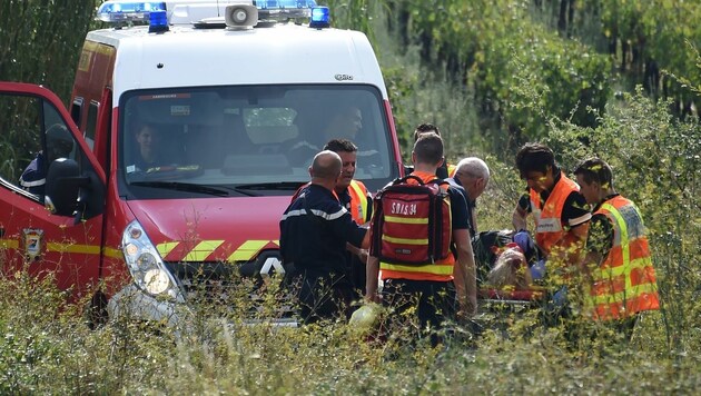 Rettungskräfte transportieren eine verletzte Person zum Rettungswagen. (Bild: APA/AFP/Sylvain Thomas)