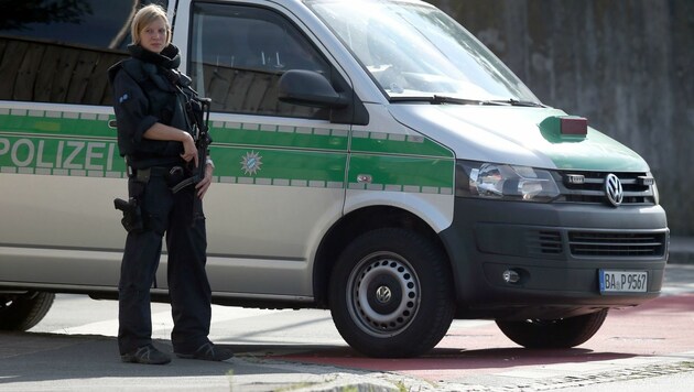 Eine schwer bewaffnete Polizistin sichert den Einsatzort in der Nähe der Erstaufnahmestelle. (Bild: APA/AFP/dpa/DANIEL KARMANN)