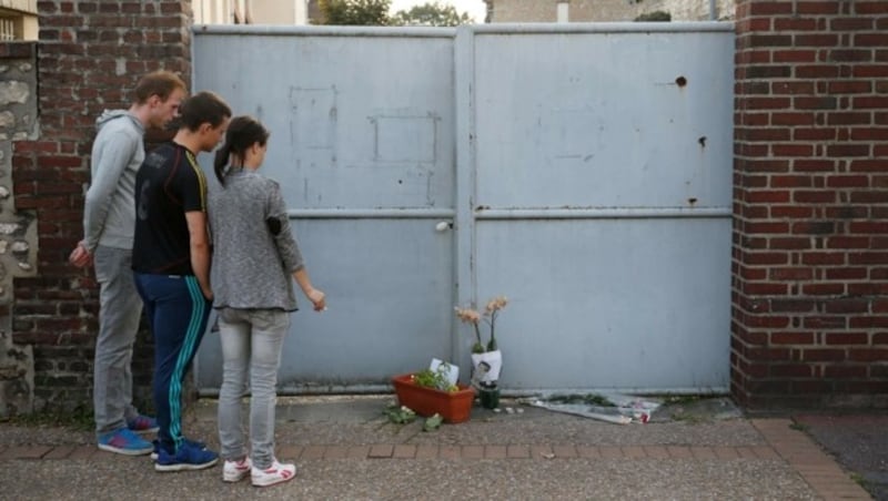 Menschen legen Blumen vor dem Haus von Pater Jacques Hamel nieder. (Bild: APA/AFP/MATTHIEU ALEXANDRE)