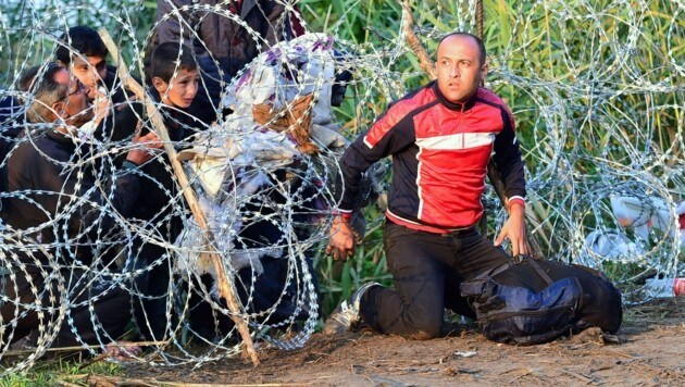 Flüchtlinge überwinden im Spätsommer 2015 eine ungarische Grenzsperre. (Bild: AFP)
