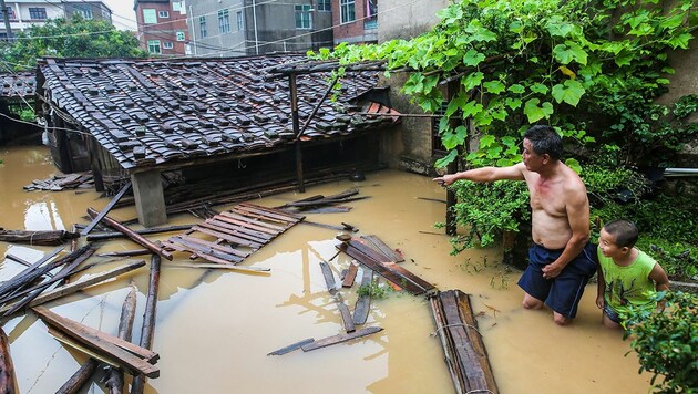Bewohner vor ihren überfluteten Häusern in der Stadt Putian (Bild: APA/AFP/STR)