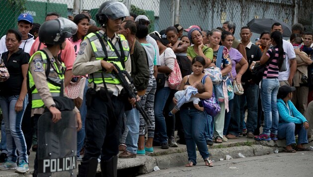Venezolaner warten vor einem bewachten Lebensmittelgeschäft in Caracas auf Einlass. (Bild: ASSOCIATED PRESS)