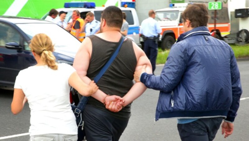 Einer der mutmaßlichen Brandstifter wird in Handschellen abgeführt. (Bild: APA/dpa/David Young)