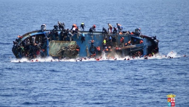 Die Aufnahme der italienischen Marine zeigt ein kenterndes Flüchtlingsboot vor der libyschen Küste. (Bild: AP)