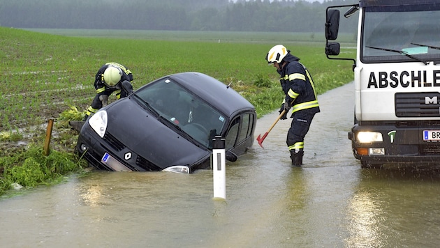 Einsatzkräfte befreien einen Pkw aus einem überfluteten Straßengraben im Bezirk Braunau in OÖ. (Bild: APA/MANFRED FESL)