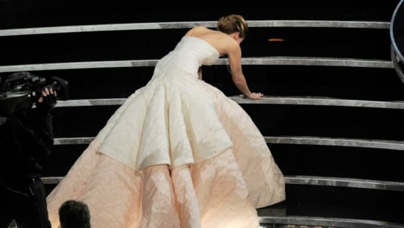 Jennifer Lawrence stolpert ihrem Oscar entegegen. (Bild: Chris Pizzello/Invision/AP)