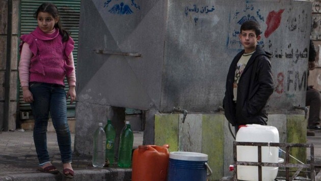 Syrische Kinder füllen Wassercontainer. Die humanitäre Lage im Land ist angespannt. (Bild: APA/AFP/KARAM AL-MASRI)