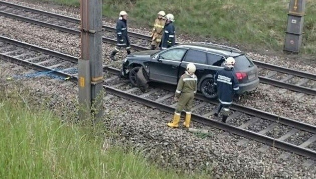 Die Feuerwehrmänner besprechen, wie sie den Audi am besten von den Gleisen wegbringen können. (Bild: FF Köstendorf)
