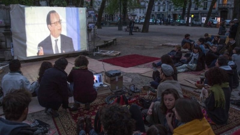 Viele Demonstranten verfolgen den TV-Auftritt von Hollande im Freien. (Bild: AFP)